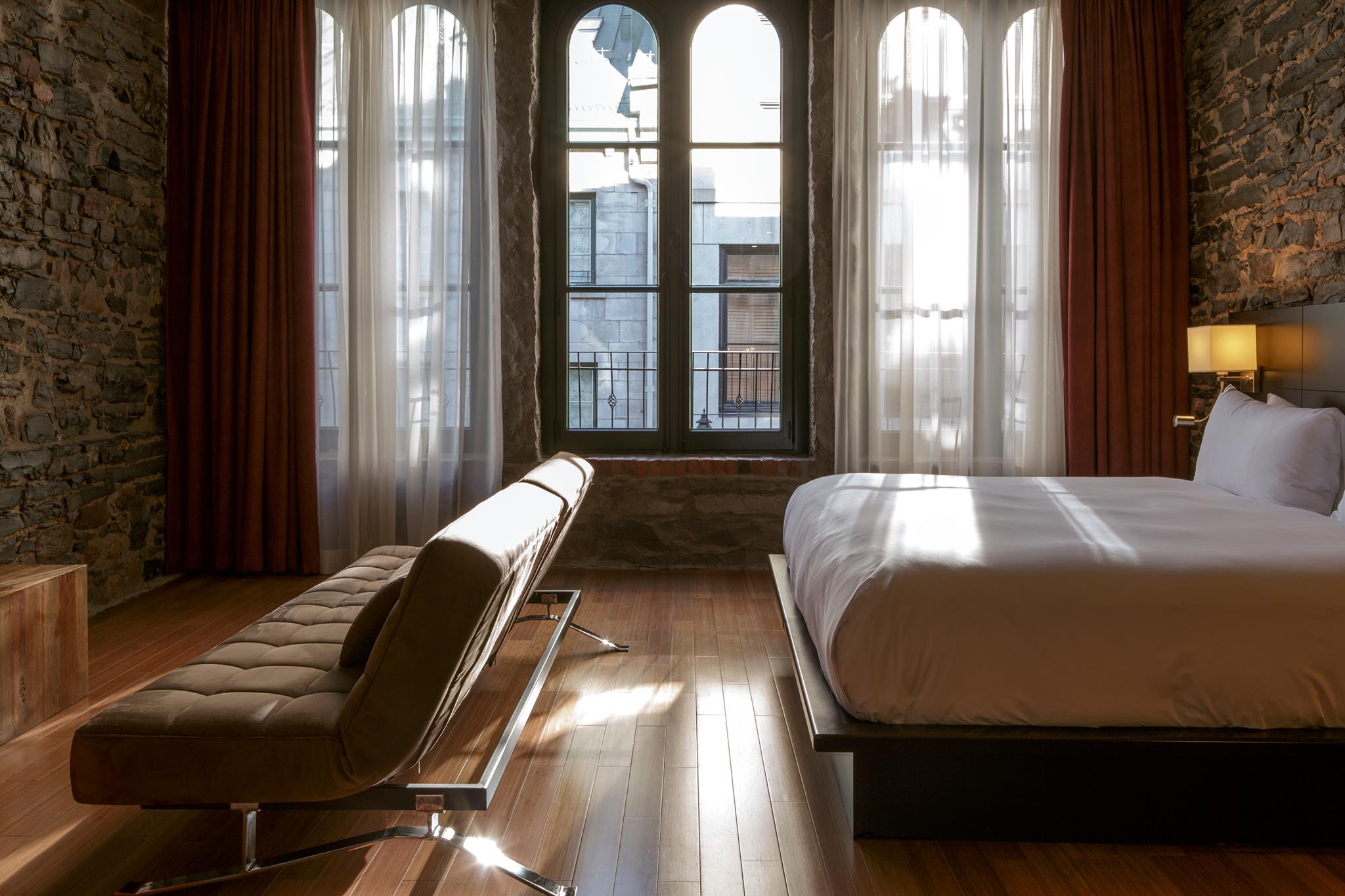 Le Petit Hôtel bedroom of boutique hotels in montreal with old exposed wlla and city view